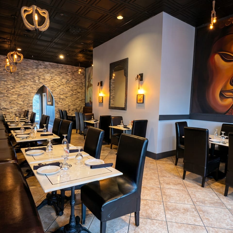 Elegant restaurant dining room with black leather booths, set tables, ornate lighting, stone walls, and a large colorful portrait mural.