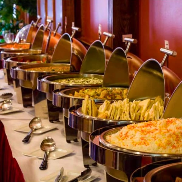 A buffet line of Indian dishes in chafing dishes, including rice, curries, and naan bread.